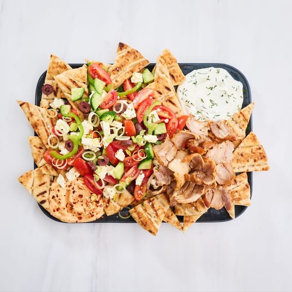 Gyro platter with sliced meat, Greek salad, pita bread, hummus, and tzatziki sauce.